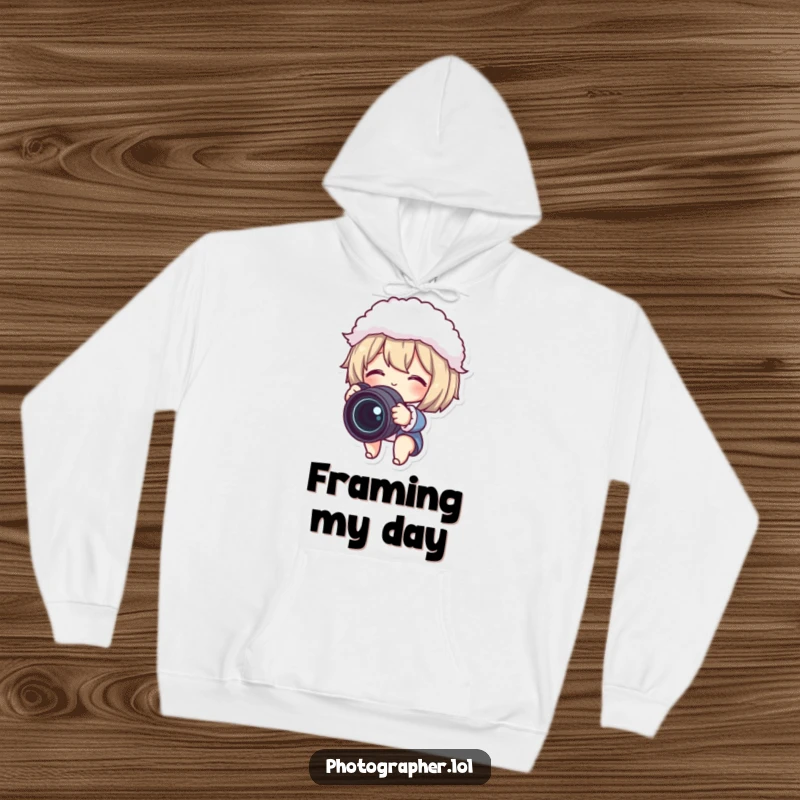 Funny hoodie with a cute character gleefully adjusting a camera lens and fluffy lens cap, perfect for cozy photo sessions.