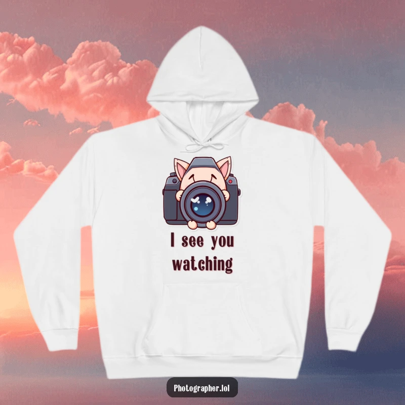 Funny hoodie with a character mischievously peeking from behind a giant camera lens, offering warmth and humor.
